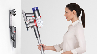 a woman is putting Dyson V7 Animal into the docking station